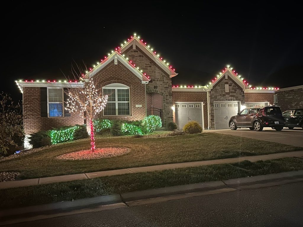 Brick home decorated with Christmas lights and lit trees