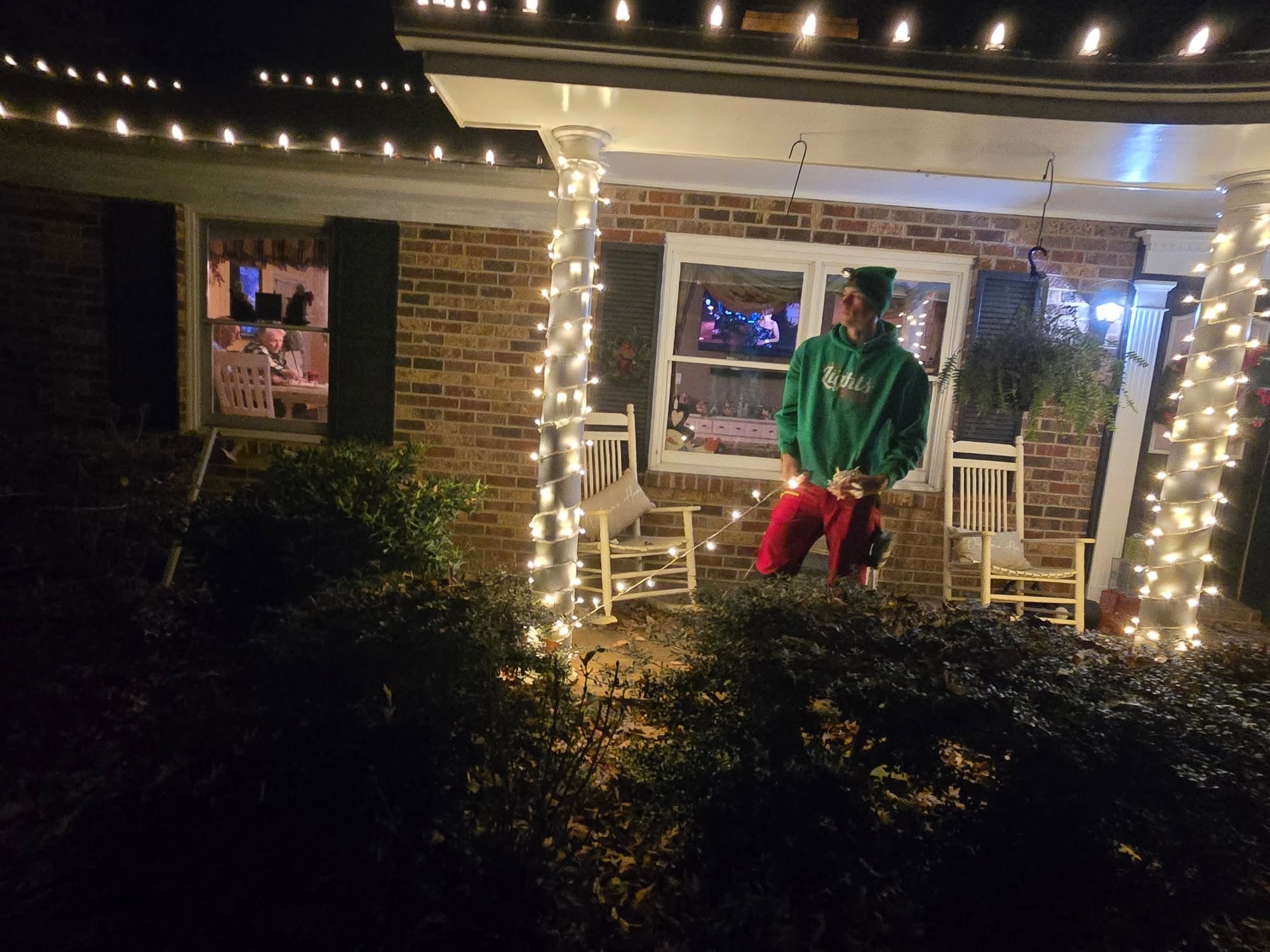 Lit holiday display around a front door featuring lit garland, a Santa Claus figure, and a decorated Christmas tree.