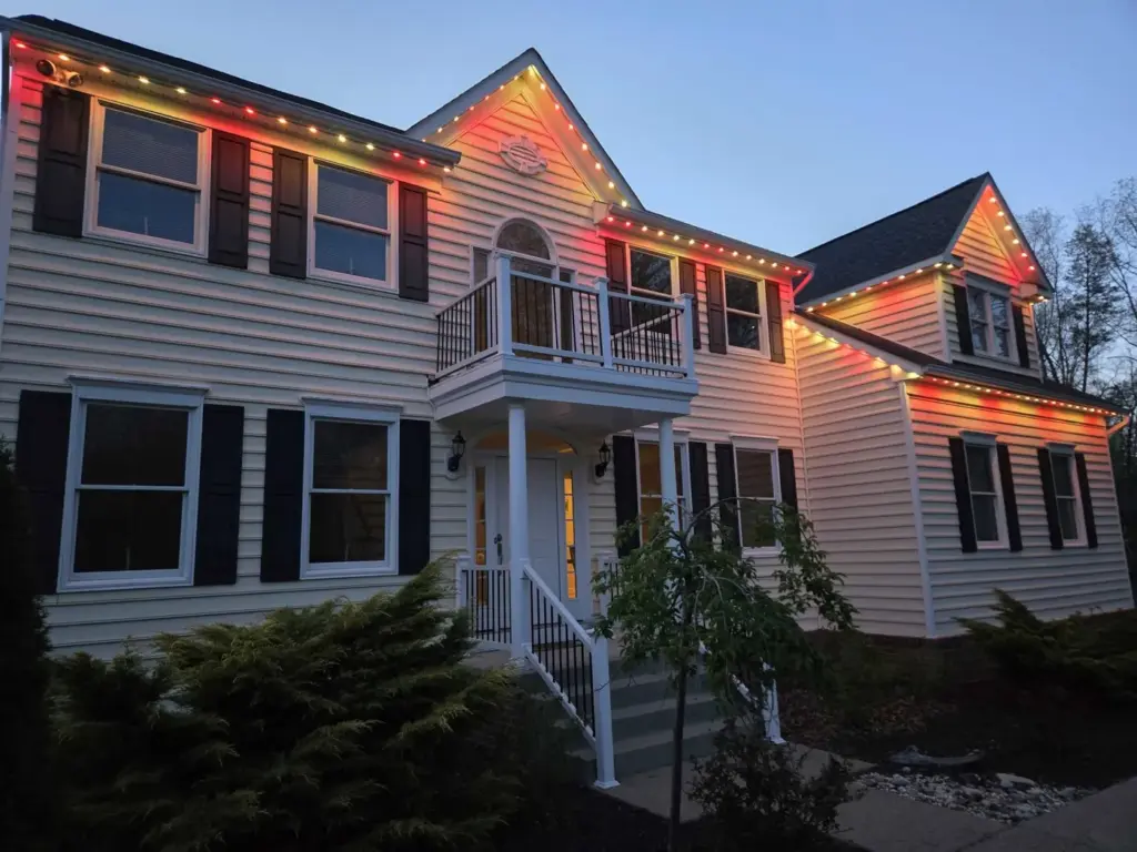 Permanent roofline lights in red and warm white on a two-story home